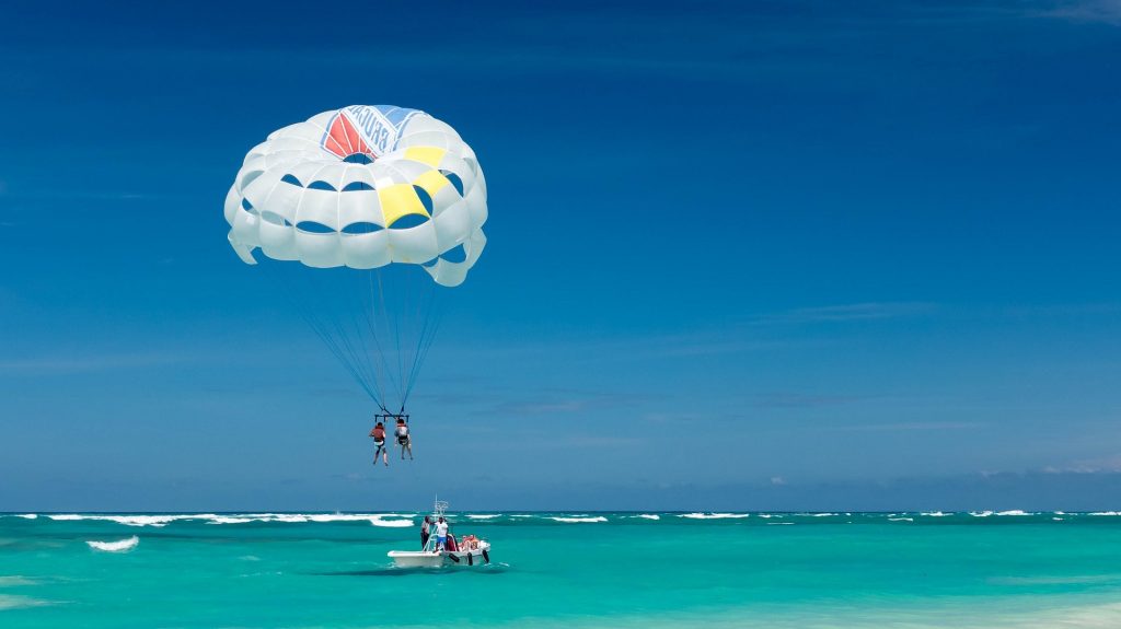 People at the beach having a nice time parasailing